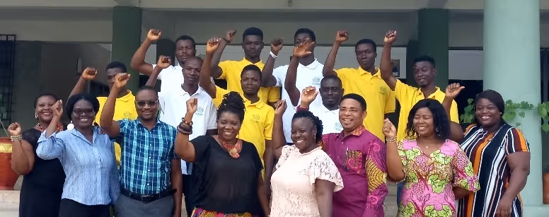 Group of men and women standing on steps with raised fists, smiling and posing for a photo.