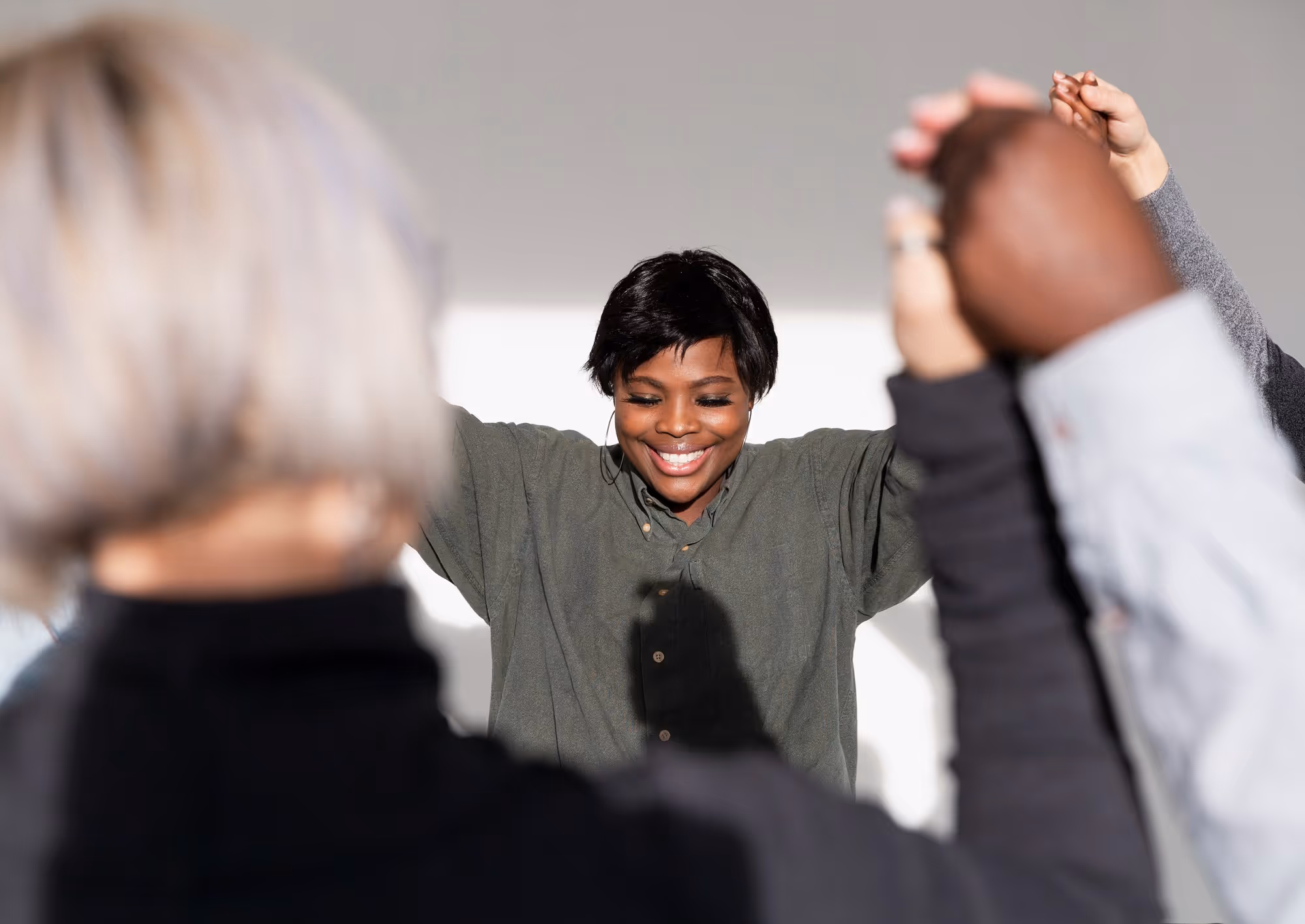 A group of Christians hold up their hands mid air and the leader prays smiling to show contentment